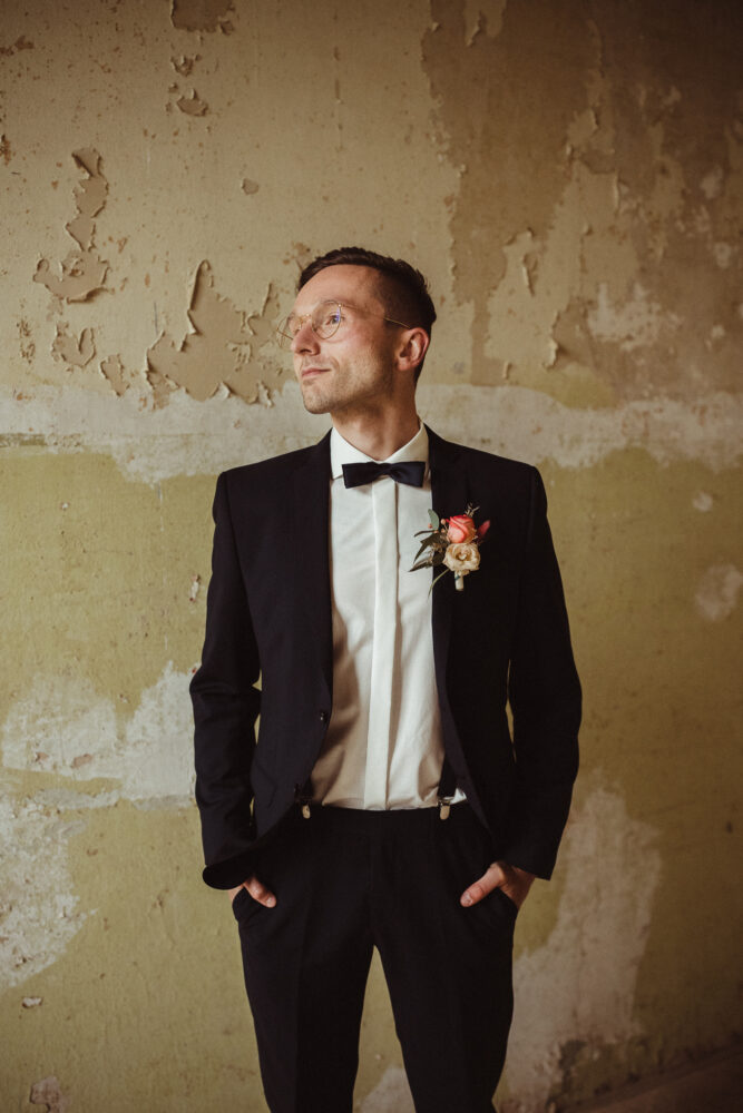 Bräutigam posiert vor alter Wand