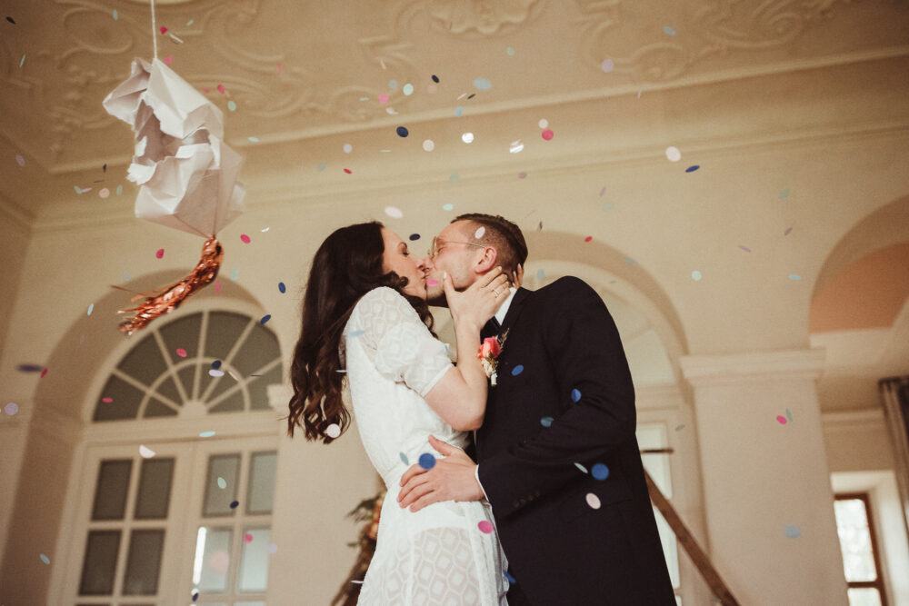 Brautpaar küsst sich im Konfettiregen