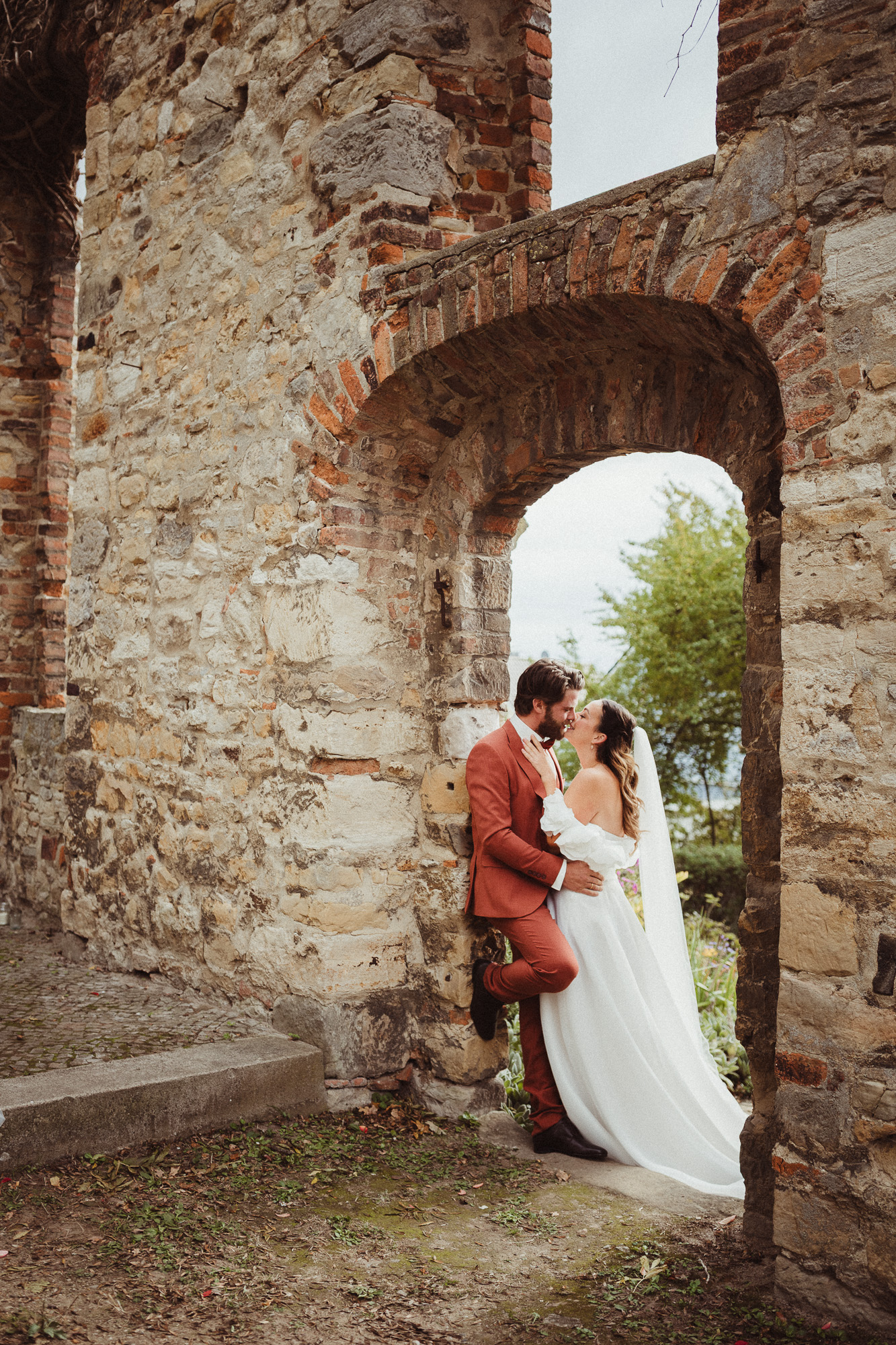 Brautpaar im Torbogen einer Mauer